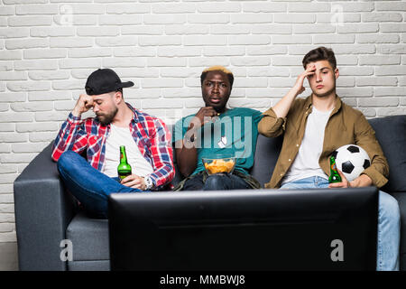 The upset friends watch a football near the table with a food Stock Photo