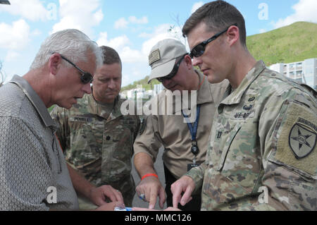 Keith Pratt, the ESF-2 Communication Task Force chief of staff in Puerto Rico for FEMA, U.S. Army Lt. Col. Dallas Powell with 56th Signal Battalion, 21st Signal Brigade in San Antonio, Texas, Gerald “Jay” English, the public safety program manager with the Department of Homeland Security and U.S. Army Capt. Sean M. White with the Joint Force Land Component Command in Puerto Rico, review a map of the locations of cellular towers that will be assessed for FEMA in Puerto Rico October 8, 2017. The group is part of a joint agency team who assessed the damage made to cellular towers in Puerto Rico b Stock Photo