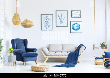 White and blue living room with sofa, armchair, lamp, posters Stock Photo