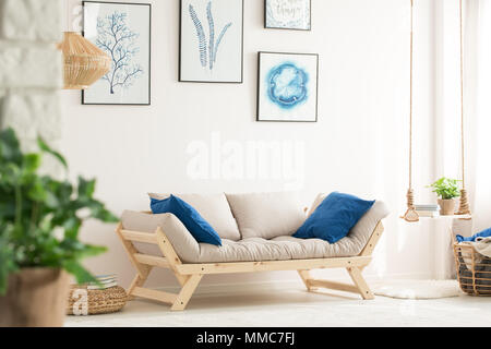 White living room with swing shelf, wood couch and posters Stock Photo