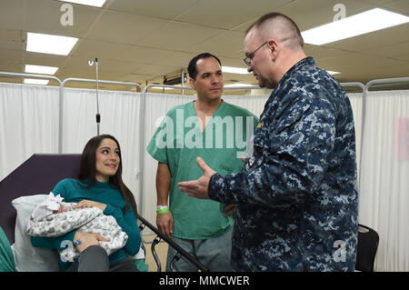 171014-N-PG340-301 CARIBBEAN SEA (Oct. 14, 2017) – Cmdr. Michael Chaney, chaplain from Naval Medical Center Portsmouth and the head chaplain embarked on the Military Sealift Command hospital ship USNS Comfort (T-AH 20), speaks to the mother and father of the first baby born on Comfort since 2010. Comfort is underway operating in the vicinity of San Juan, Puerto Rico. The Department of Defense is supporting the Federal Emergency Management Agency, the lead federal agency, in helping those affected by Hurricane Maria to minimize suffering and is one component of the overall whole-of-government r Stock Photo