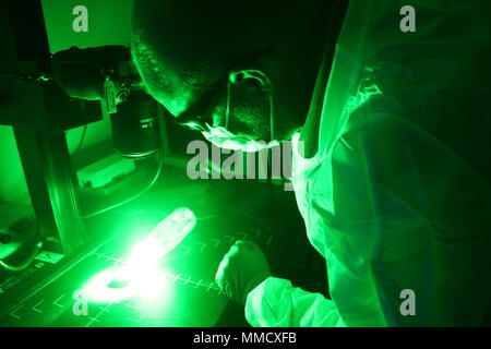A Latent Print Technician assigned to the Forensic Exploitation Laboratory of United States Army Central Command performs fingerprint recovery in Southwest Asia on October 9, 2017. The archival image records the application of laser technology to identify latent prints retained for ongoing and future military investigations. Stock Photo