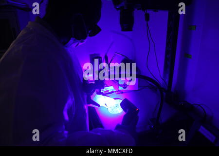 A Latent Print Examiner assigned to the Forensic Exploitation Laboratory of United States Army Central Command performs fingerprint recovery in Southwest Asia on October 9, 2017. The archival image records the application of a blue laser to a compact disc surface to reveal latent prints for investigative use. Stock Photo