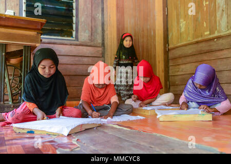 Krabi, Thailand - May 2, 2015: Cute Muslim girls drawing pattern on Batik fabric for painting in their home in Krabi, Thailand Stock Photo