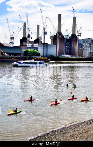 London,England, UK. Batersea Power Station and construction cranes seen from the North bank of the River Thames. Group of children in canoes Stock Photo