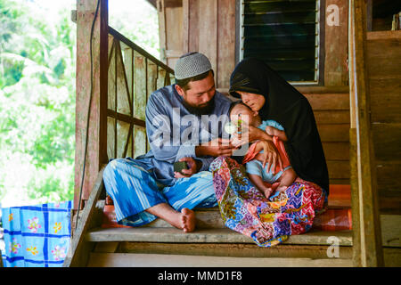 Krabi, Thailand - May 2, 2015: Muslim family feeding milk to their child together in their home in Krabi, Thailand Stock Photo