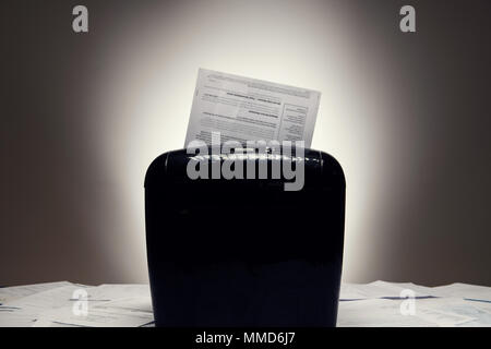Office shredder on pile of paperwork with personal documents being shredded. Stock Photo