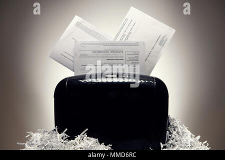 Office shredder and personal documents being shredded, with piles of shredded paper. Stock Photo