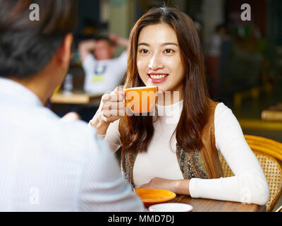 young asian couple lovers sitting at table chatting talking face to face in coffee shop. Stock Photo