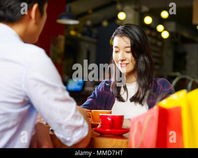 young asian couple lovers sitting at table chatting talking in coffee shop after shopping. Stock Photo