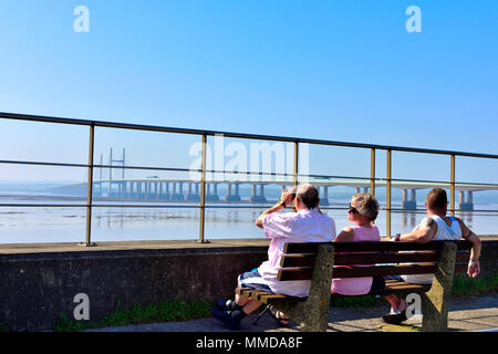 People on seat overlooking Severn Estuary with M4, Second Severn Crossing bridge Stock Photo