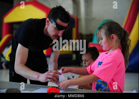 A U.S. Air Force Airman from the 563rd Rescue Group helps a child build a paper airplane during the 563rd RQG’s annual Spouse Appreciation Day at Davis-Monthan Air Force Base, Ariz., March 17, 2018. While the Airmens’ spouses were enjoying orientation flights, their children were treated to a bounce castle and inflatable slide. (U.S. Air Force Stock Photo