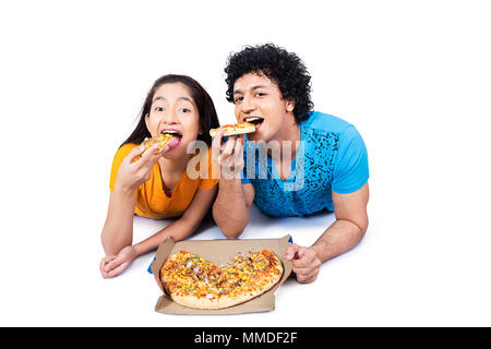 Two Young Couple Boy And Girl Lying Floor Eating Tasty-Pizza Stock Photo