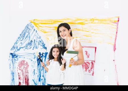 Happy mother and Kid daughter Showing paintbrush makes repairs At-home Stock Photo