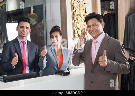 Two Receptionist And Businessman Hotel Booking And Talking Telephone Thumbs-up Stock Photo