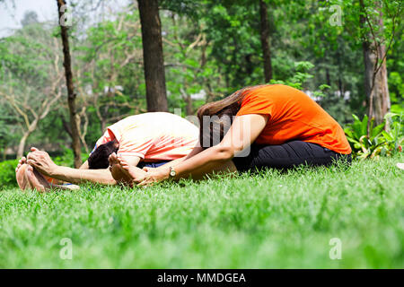 Married Couple Sitting Grass Yoga Stretching Fitness Exercising Practice In-Park Stock Photo