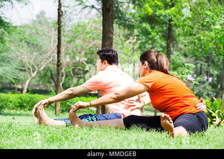 Two Couple Doing Yoga Fitness Exercise Stretching Flexibility Workout In-Garden Stock Photo