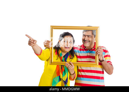 Happy Two Senior Couple holding picture frame Looking-throw Pointing Showing