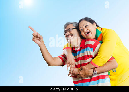 Cheerful Married-Couple Piggyback Riding Pointing-up Showing Fun Enjoy Outdoors Stock Photo