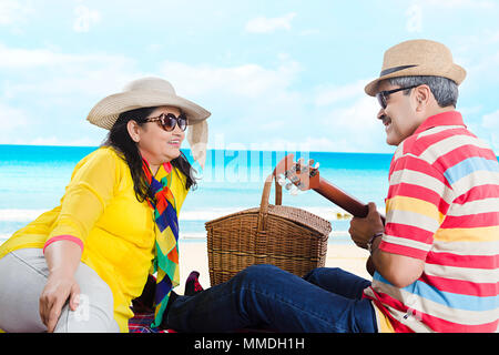 Happy Senior couple love having picnic with guitar in Sea-Beach Enjoy Stock Photo