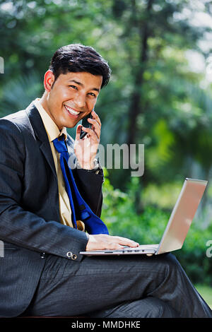 Businessman using a laptop in a park Stock Photo - Alamy