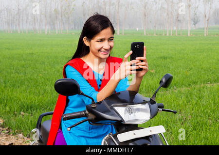 One Villager Teenage Girl Sitting Scooter, Reading Text-Message Mobile-Phone Farm Stock Photo