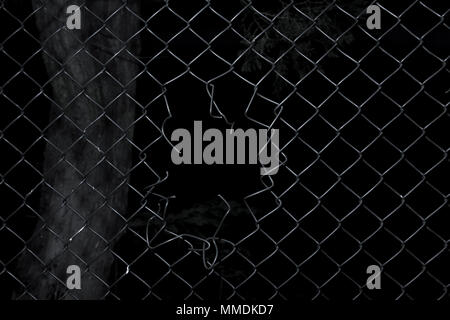 Ripped wire fence with black background. Stock Photo