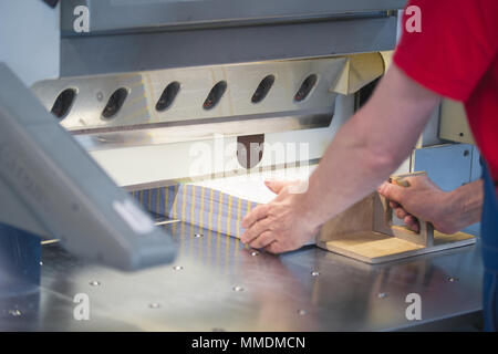 Hands of worker working on cutter guillotine machine in a printing factory Stock Photo