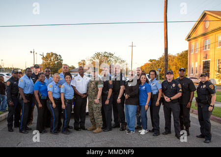 Marines, community members and officers with the New Orleans Police Department pose for a photo outside of The Village at Federal City, New Orleans, Oct. 17, 2017. “A Night Out Against Crime” is a yearly event in which Marines and police officers within the NOPD bring together community members to raise awareness of police officer presence. The event involved military and civilian officers allowing children to sit in a patrol vehicle, a pumpkin-patch dash, a prize drawing and free concession snacks for all those in attendance. (U.S. Marine Corps photo by Cpl. Dallas Johnson/Released) Stock Photo