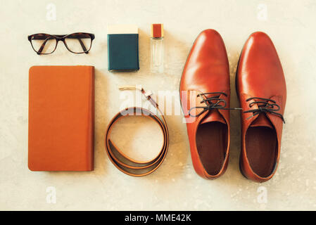 Men's accessories and shoes on gray background. Flat lay of elegant belt, glasses, parfume, notebook. Stylish set and fashion concept for man Stock Photo