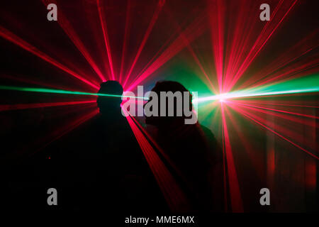 Silhouette of a group of people dancing at a disco with laser lights. Stock Photo