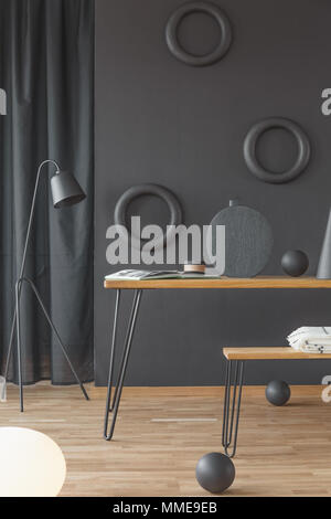 Black room interior with a wooden table and stool, lamp and decorations Stock Photo