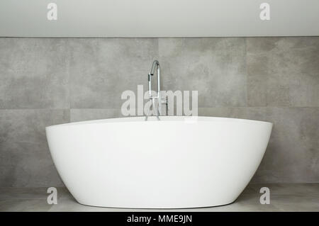 White ceramic bathtub with a steel faucet on grey background