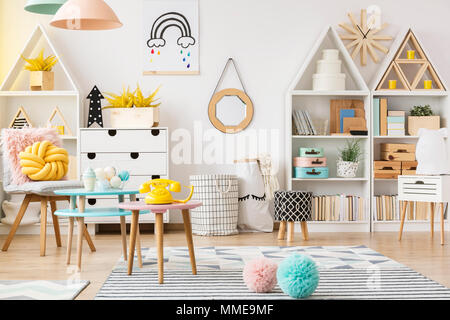 Two pink and blue pompoms lying on the floor with carpets in bright playroom interior for children Stock Photo