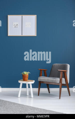 Wooden end table with fresh plant in glass vase standing between grey and  mustard armchairs in white minimal room interior Stock Photo - Alamy