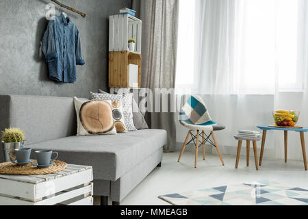 New style flat in grey with sofa, small table, chair, pattern carpet and beautiful home decorations Stock Photo