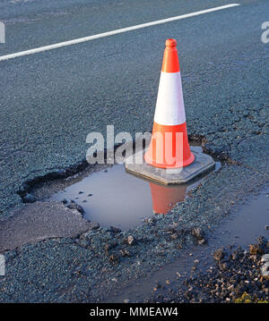 traffic cone marking giant water filled pothole on road york yorkshire united kingdom Stock Photo
