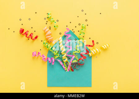 Envelope with party confetti explosion on yellow background. Invitation card, flat lay. Stock Photo