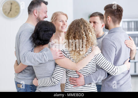 People having group hug during therapy in rehab Stock Photo