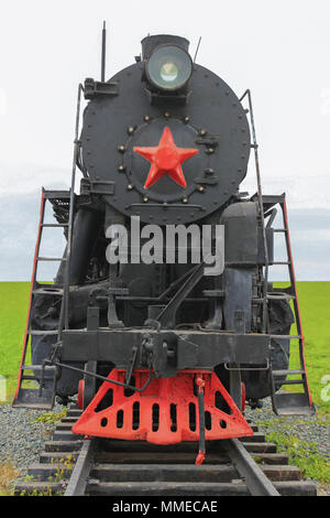 Old soviet locomotive, front view, on the background of green meadows Stock Photo