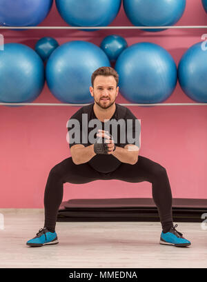 Young man doing stretching exercises in a gym Stock Photo