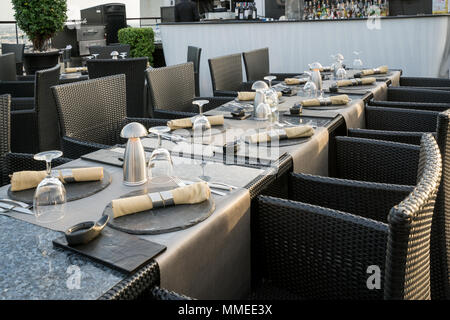 Shot of a restaurant table with empty glasses and a plate with a napkin on top in rooftop bar restaurant. Stock Photo