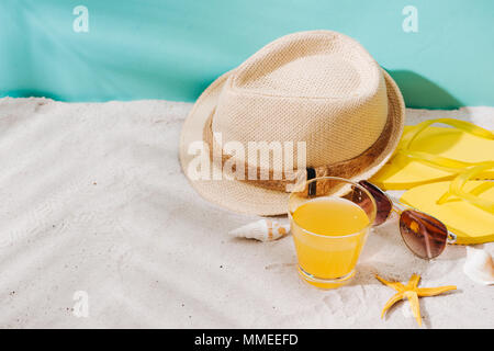 Summer background. Beach accessories flip flops, sunglasses, hat and orange juice on sand background Stock Photo