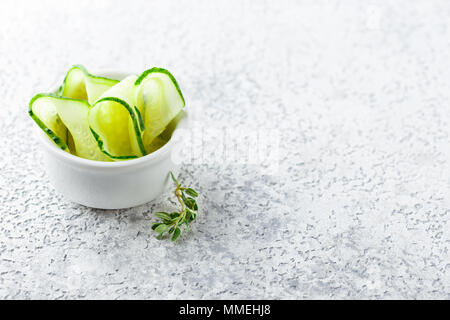 Slices of fresh cucumbers in a bowl on light background. Stock Photo