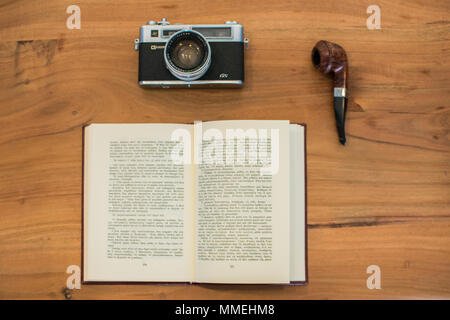 Vintage photo camera, a book and a pipe on a table Stock Photo