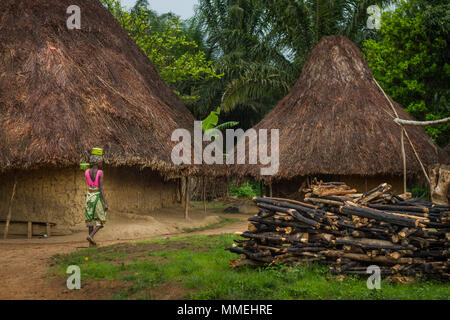 YONGORO, SIERRA LEONE - June 06, 2013: West Africa, unknown woman carries a pot on the head next to the village huts near the capital Freetown, Sierra Stock Photo