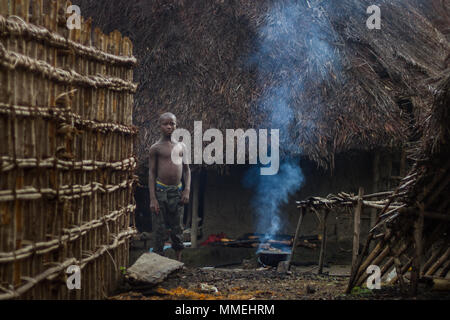 YONGORO, SIERRA LEONE - June 06, 2013: West Africa, unknown boy next to the village huts with the fire smoke lit for food preparation near the capital Stock Photo