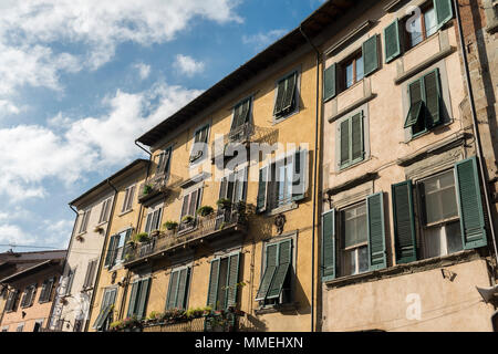 Facades with windows of houses of Pisa, on a sunny day with a blue sky with white clouds in the background. Stock Photo