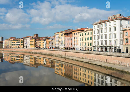 Facades of buildings on the banks of the Arno River on its way through Pisa on a dreamy day, with the reflection of the buildings in the foreground an Stock Photo