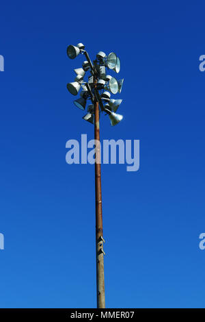 Rusty sport light post in a stadium against a deep blue sky. Stock Photo